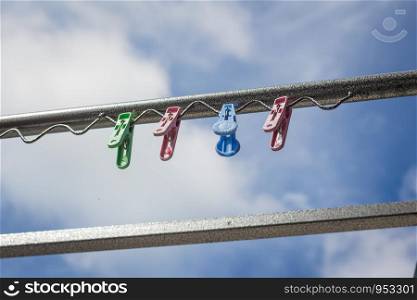 Plastic clothespin on a clothesline and in the daytime sky.