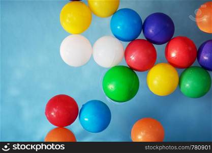 Plastic colored balls in the children?s pool on the background of blue water. Plastic colored balls in the children?s pool