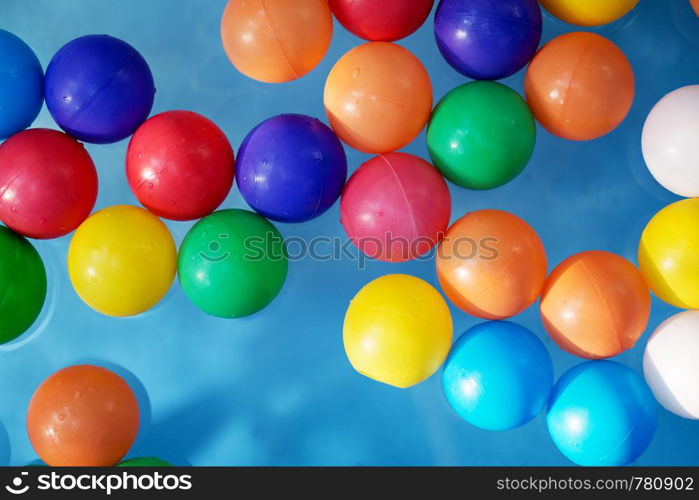 Plastic colored balls in the children?s pool on the background of blue water. Plastic colored balls in the children?s pool