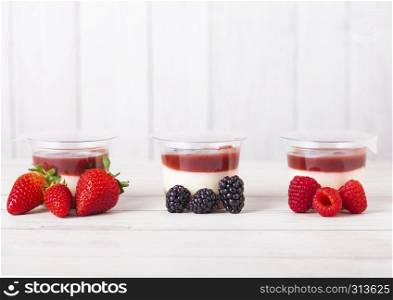 Plastic container with berries cream dessert on wooden background with fresh summer berries