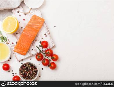 Plastic container with fresh salmon slice with oil tomatoes and lemon on stone kitchen background