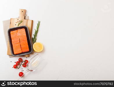 Plastic container with fresh salmon slice with oil tomatoes and lemon on stone kitchen background