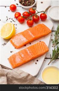 Plastic container with fresh salmon slice with oil tomatoes and lemon on wood kitchen background