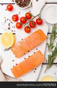 Plastic container with fresh salmon slice with oil tomatoes and lemon on wood kitchen background
