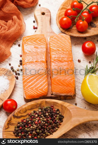 Plastic container with fresh salmon slice with pepper tomatoes and lemon on wooden kitchen background