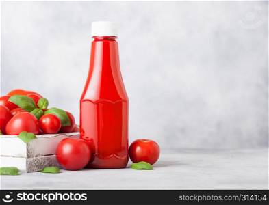 Plastic container with tomato ketchup sauce with raw tomatoes on kitchen background.