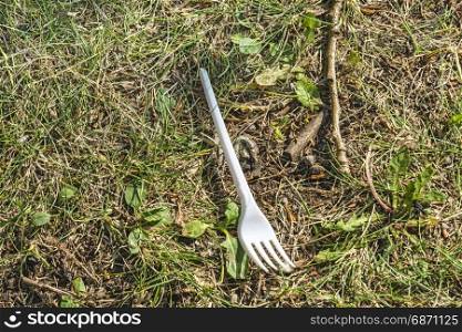Plastic disposable fork on green grass