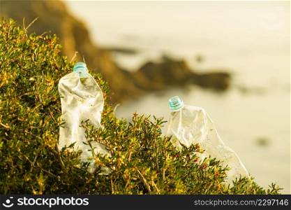 Plastic empty water bottle abandoned on coast. Environmental pollution global ecological problem. Earth ecology.. Plastic empty water bottle abandoned on nature