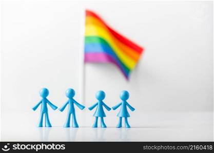 Plastic figures of gay and lesbizn couples and LGBT rainbow flag on light gray background. The concept of discrimination of same-sex families. Gays and lesbians