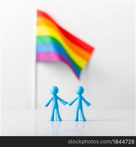 Plastic figures of gay couple and LGBT rainbow flag on light gray background. Equal rights for lgbtq community concept