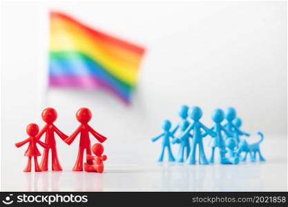 Plastic figures of gay couple with children, LGBT rainbow flag and heterosexuals on light gray background. Equal rights for lgbtq community concept