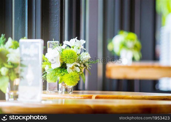 Plastic Flower In Glass On Wooden Table.