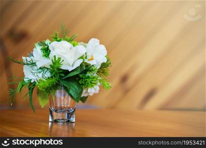 Plastic Flower In Glass On Wooden Table And Soft Light For Background.
