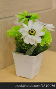 plastic flowers in white vase on table