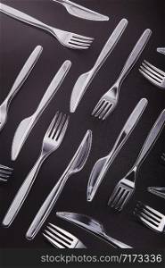 Plastic forks and knives scattered over red background. Collecting plastic waste to recycling. Concept of plastic pollution and too many plastic waste. Copy space at the top
