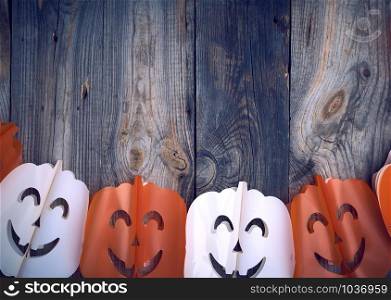 plastic garland on with carved figures of pumpkins, gray wooden background, backdrop for Halloween