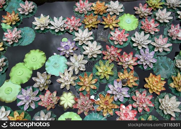 Plastic lotuses on the surface of pond in buddhist temple, China