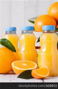 Plastic mini bottles of organic fresh orange juice with raw oranges in white wooden box