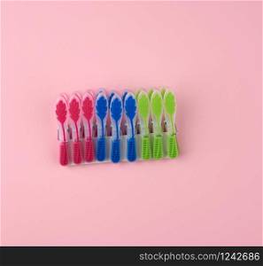 plastic multi-colored clothespins on a pink background, top view