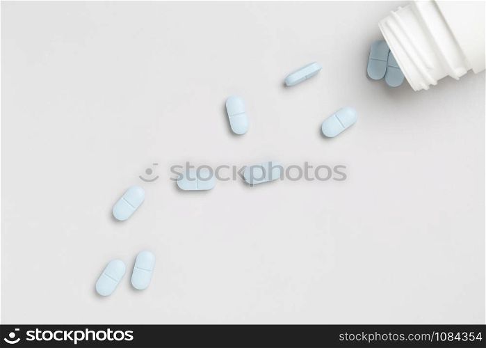 Plastic pills bottle and blue medicine pills on a single color background. Plastic pills bottle and colorful medicine pills on a single color background
