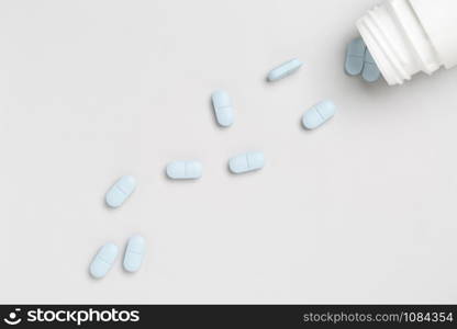 Plastic pills bottle and blue medicine pills on a single color background. Plastic pills bottle and colorful medicine pills on a single color background