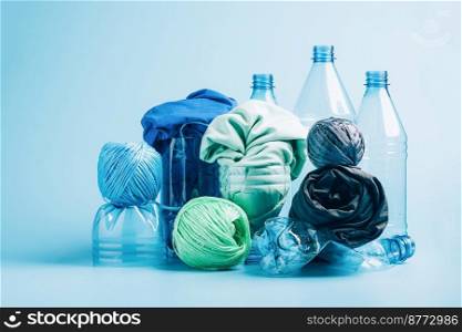 Plastic recycling and reuse concept. Empty plastic bottle and various fabrics made of recycled polyester fiber synthetic fabric on a blue background. Environmental protection waste recycling.. Empty plastic bottle and various fabrics made of recycled polyester fiber synthetic fabric on a blue background
