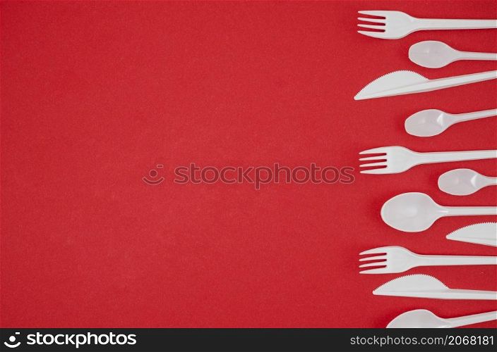 plastic spoon fork arranged row bright red backdrop