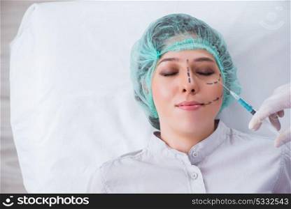 Plastic surgeon preparing for operation on woman face
