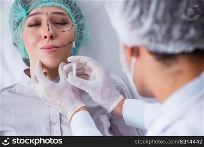 Plastic surgeon preparing for operation on woman face