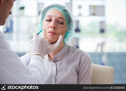 Plastic surgeon preparing for operation on woman face