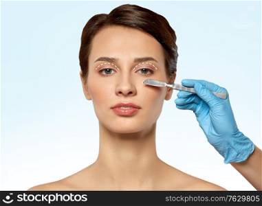 plastic surgery, blepharoplasty and beauty concept - beautiful young woman and hand with scalpel over blue background. beautiful young woman and hand with scalpel