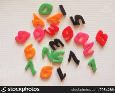 Plastic toy numbers. Plastic toy magnetic numbers from zero to nine in random order over white corrugated cardboard