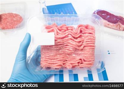 Plastic tray raw fresh ground meat in lab scientist hand. Laboratory meat quality analysis inspection check or cultured meat concept.