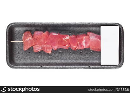 Plastic tray with fresh raw pork beef kebab on wooden stick with label