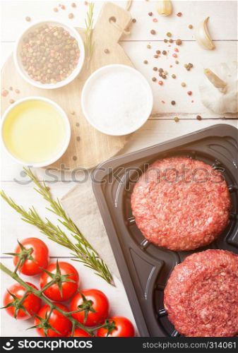 Plastic tray with raw minced homemade grill beef burgers with spices and herbs. Top view and space for text.