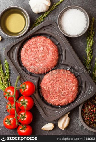 Plastic tray with raw minced homemade grill beef burgers with spices and herbs. Top view.