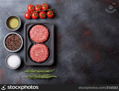 Plastic tray with raw minced homemade meat beef burgers with spices and herbs. Top view and space for text.