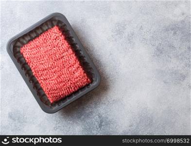 Plastic tray with raw minced homemade meat with spices and herbs. Top view and space for text on kitchen table background