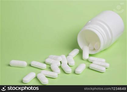 Plastic white bottles of pills on a green background of scattered white drugs. Plastic white bottles of pills on a green background of scattered white pills