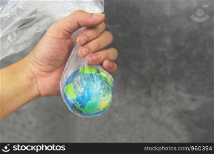 Plastic world or World Environment Day Concept / Hand holds the planet earth in a plastic bag ban say no plastic pollution zero waste recycle
