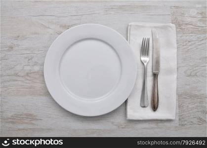 Plate, cutlery and cloth on wood
