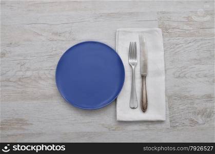 Plate, cutlery and cloth on wood