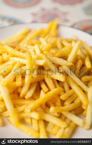 Plate full of crispy fries on a table with tablecloth