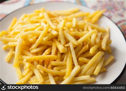 Plate full of crispy fries on a table with tablecloth