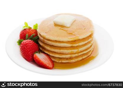 Plate full of fluffy golden pancakes with strawberries and maple syrup