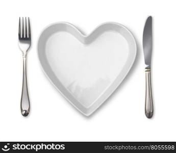 plate in shape of heart, table knife and fork isolated on white