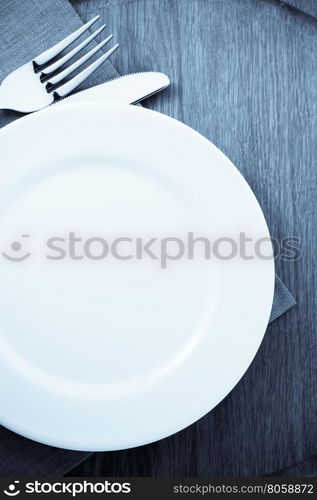 plate, knife and fork at cutting wooden board