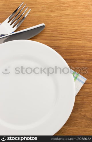 plate, knife and fork at cutting wooden board