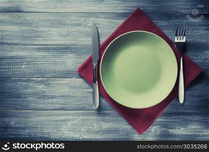 plate, knife and fork at napkin on wood. plate, knife and fork at napkin on wooden background