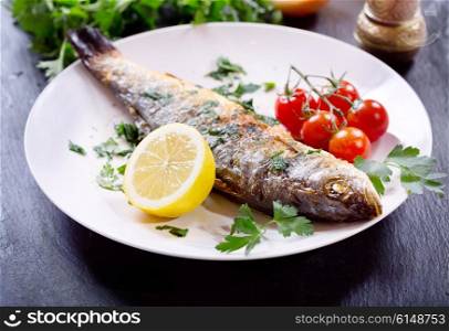 plate of baked sea bass on dark background